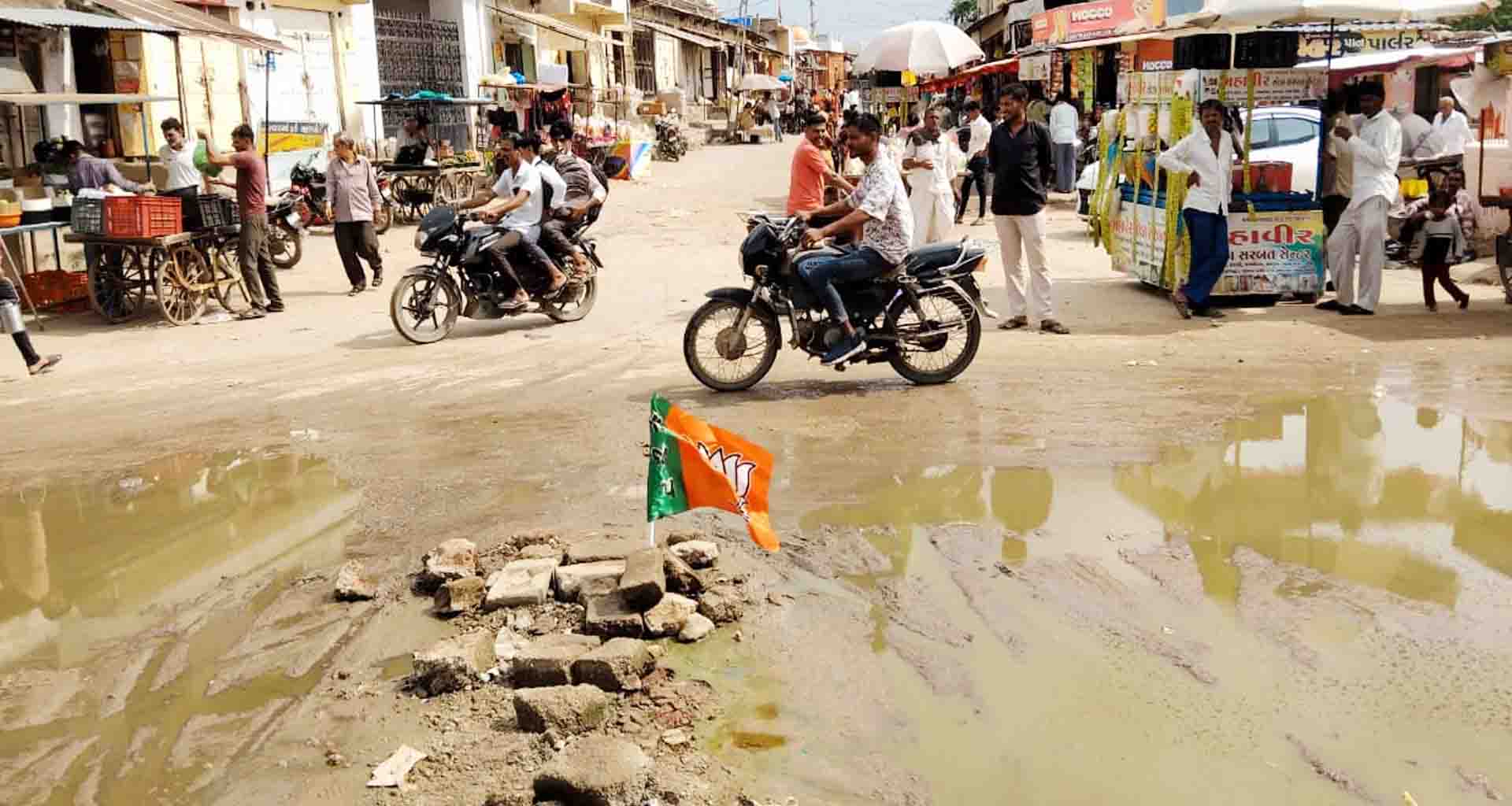 વાવ શહેરમાં રોડના અભાવે ખાડા અને કાદવ કીચડનું સામ્રાજ્ય વધતાં યુવકે ભાજપનો ધ્વજ મૂકી વિરોધ નોંધાવ્યો